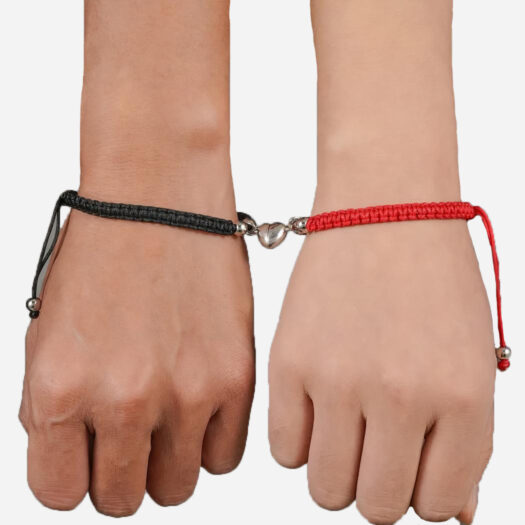 Deux bracelets tressés avec un cœur aimanté qui les relie, portés sur des poignets.