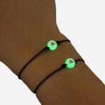 Poignet avec deux bracelets phosphorecents avec un coeur.