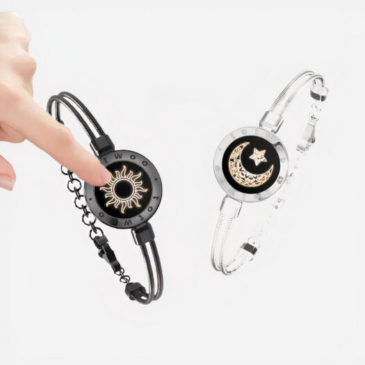 Photo montrant un bracelet couple connecté, l'un argenté et l'autre noir avec un boîtier central tactile qui envoie des messages.