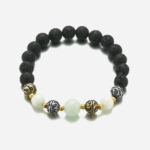 Photo d'un bracelet en pierres volcaniques et perles phosphorescentes sur un elastique.