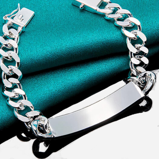 Gourmette argentée posée sur un tissu bleu canard.