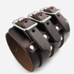 Photo d'un bracelet manchette marron en cuir large de style punk rock à trois boucles en acier et rivets.