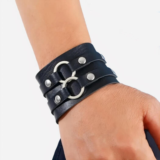 Photo d'un bracelet de force en cuir noir à rivets et anneaux en alliage sur un bras