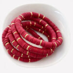 Bracelets en perles plates rouges posés sur une assiette
