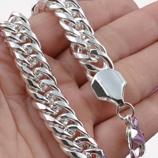 Bracelet chaine en argent tenu par une main.