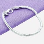 Bracelet chaine en argent sur fond violet et gris.
