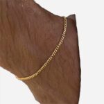 Bracelet doré avec une chaine fine sur un poignet.