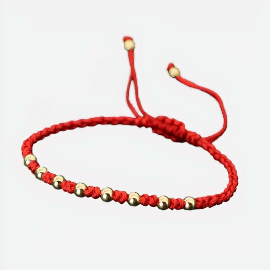 Un bracelet cordon rouge avec des perles dorées