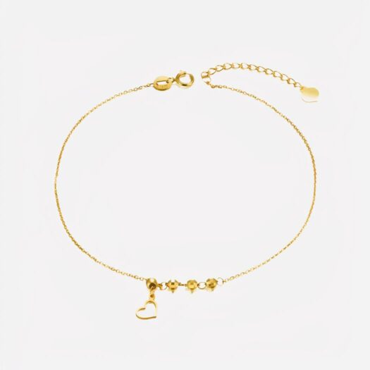Photo d'un bracelet de cheville en or jaune pour femme avec coeur en pendentif et trois perles rondes à facettes, le tout sur un fond blanc