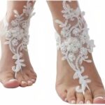 Photo de pieds de femme portant des bracelets en dentelle blanche rehaussés de perles blanches également, le fond est blanc