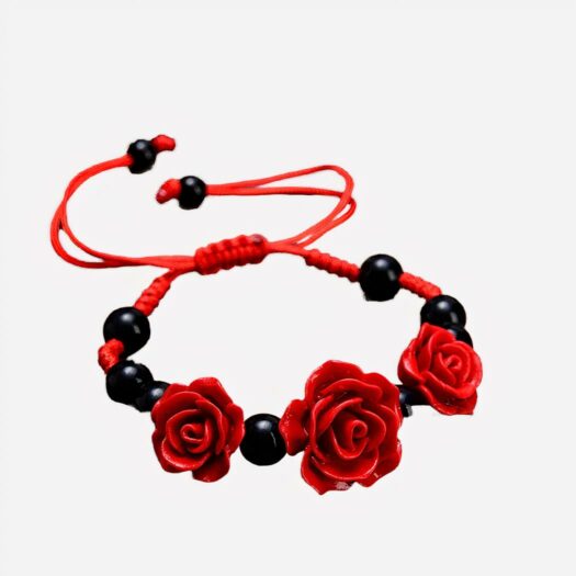 Un bracelet rouge avec des perles noires et 3 roses rouges posé sur une table