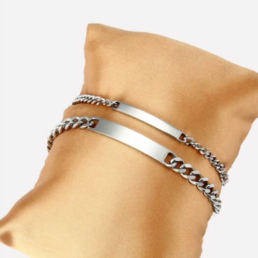 On voit deux gourmette sur un support doré.