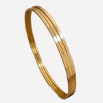 3 bracelet joncs doré posés sur un tissu beige