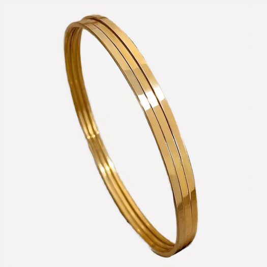 3 bracelet joncs doré posés sur un tissu beige