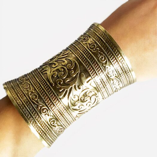 Photo d'une manchette longue aux détails travaillés, de couleur bronze antique sur l'avant-bras d'une femme, le tout sur un fond blanc