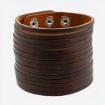 Photo d'un bracelet manchette large marron en cuir marron découpé et fermeture par pressions, sur un fond blanc