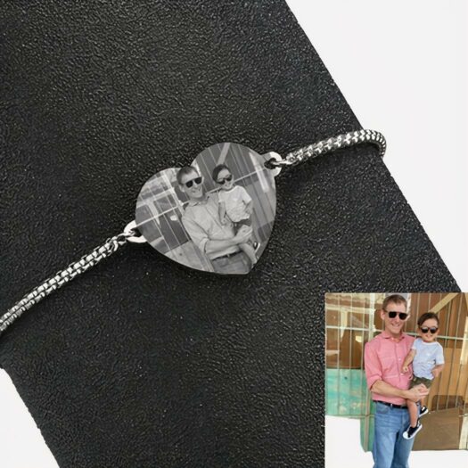 Bracelet argenté avec un coeur où apparait un enfant et un homme. En bas il y a une petite hoto en couleur d'un homme qui porte un enfant. Le bracelet entoure un tube noir