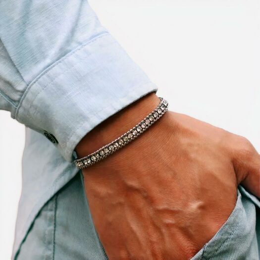 Photo d'un homme habillé en total look jean la main dans la poche et portant un bracelet tennis argenté orné de zircons blancs