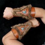 2 avant bras entourés de 2 bracelets en cuirs et en fourrure marron. Présence de perles sur le dessus