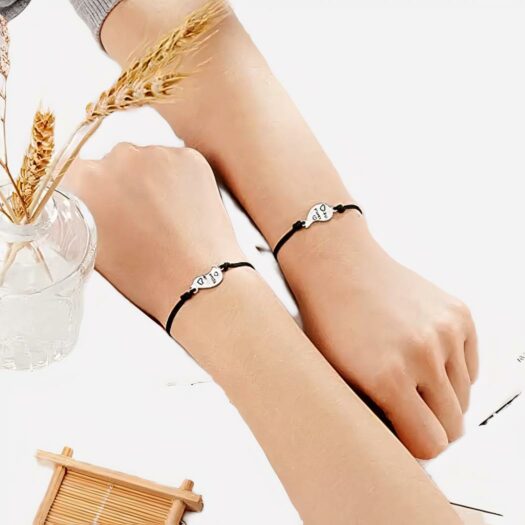 Deux mains avec des bracelets de l'amitié noirs dessus