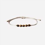 Photo d'un bracelet oeil de tigre marron avec cordon beige pour garçons et adolescents réglable sur un fond gris