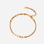 Un bracelet doré fermé avec de grandes mailles et de petites mailles. Une petite chaine d'ajustement avec un petit pendentif
