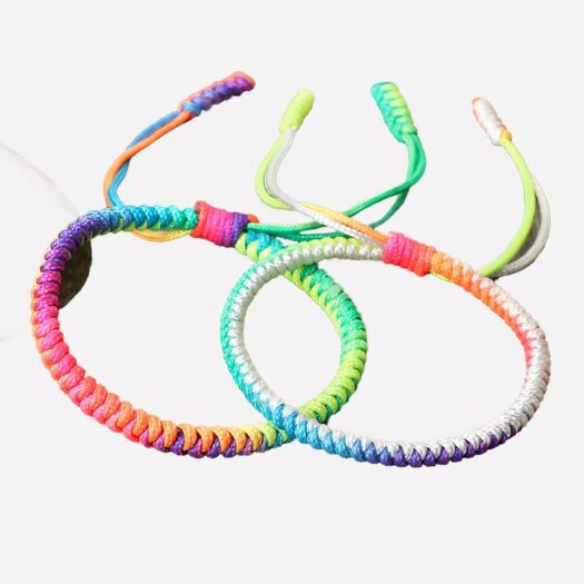 2 bracelets en fils multicolores posés sur une table en bois