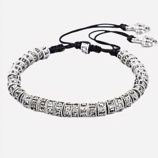Photo d'un bracelet tibétain perles en alliage de zinc avec mantras au look vintage et fermeture réglable par cordon noir en coton avec noeud, sur un fond gris clair