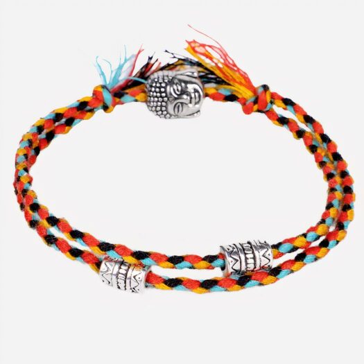 Bracelet tibétain en fils de coton à dominance orange tissés et t^te de bouddha argenté avec deux ranges et perles argentées mantras le tout sur fond gris clair