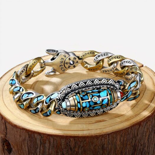 Photo d'un bracelet tibétain et bouddhiste an alliage argenté et doré aux six mantras et turquoises naturelles posé sur un rondin de bois avec fond noir et fumée blanche