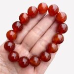 Main tenant un bracelet rouge.