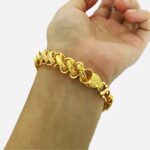 Poignet portant un bracelet en or.