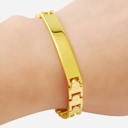 Photo d'un bracelet gourmette pour femme plaqué or avec longue plaque et maillons sur pivots sur le poignet d'une femme le tout sur fond blanc