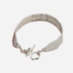 Bracelet maille en argent sur fond rose.