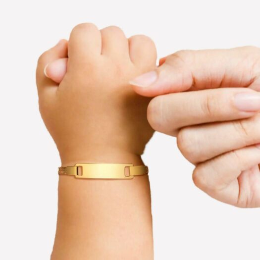 Une main d'enfant portant une gourmette dorée entoure le doigt d'une main d'adulte