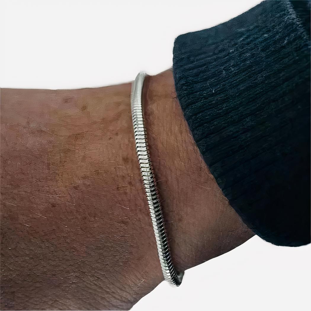 7552-ellijq.jpg Un poignet d'homme porte un bracelet argenté. Le bas d'une manche bleue marine apparait