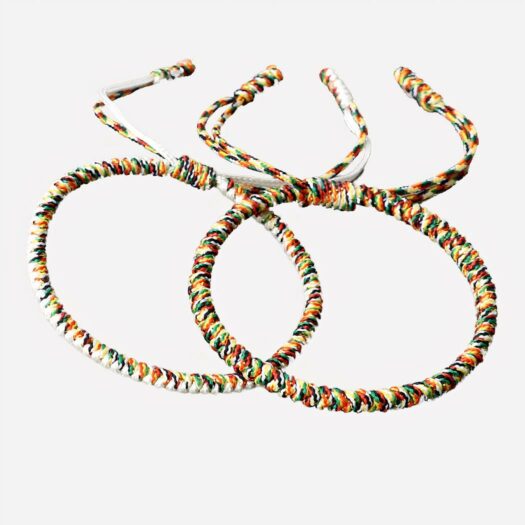 2 bracelets brésiliens ronds, un multicolore et un blanc et multicolore. Ils sont posés sur une table en bois