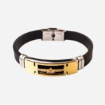 Bracelet ado garçon avec un aigle. Le bracelet est en silicone noir. Le fermoir en acier gris. Le rectangle où se trouve l'aigle est doré. Un élément de chaque côté est gris. Sur fond uni blanc.