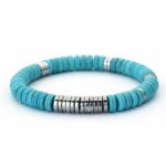 Photo d'un bracelet pour homme en perles plates turquoise et hématite sur un rocher noir