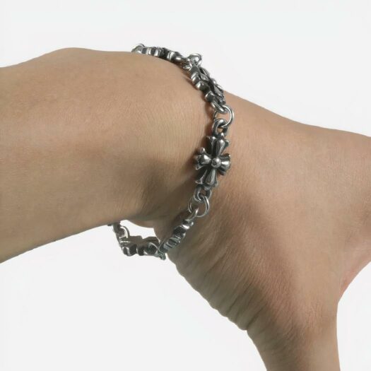 Un poignet entouré d'un bracelet argenté dont les maillons sont en forme de croix